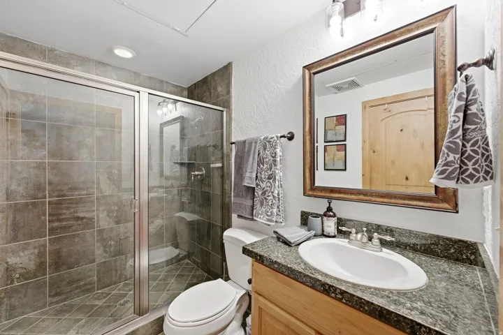 Bathroom featuring a glass-enclosed shower with tile surround, a built-in shower bench, and recessed lighting