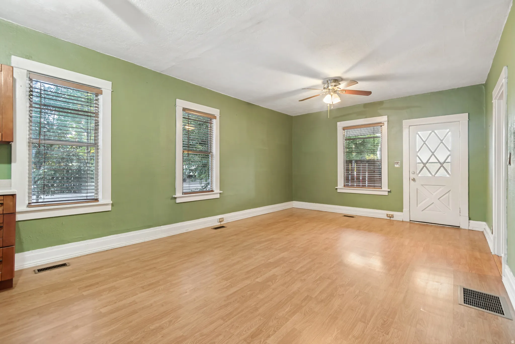 Spacious room featuring wood-finish flooring, light green walls, and white trim
