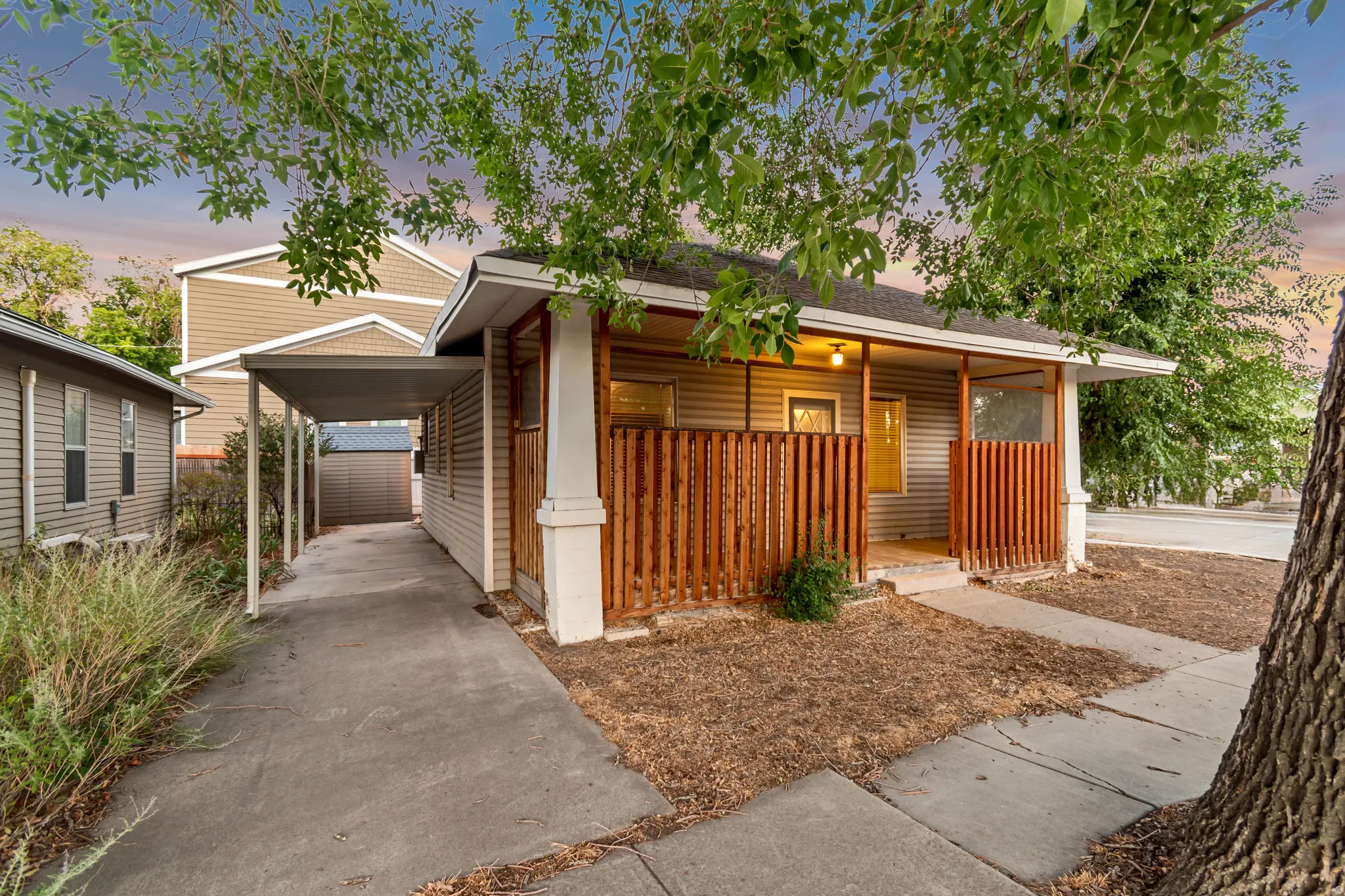 Exterior featuring a covered carport, a welcoming covered front porch with vertical wood slatted railing, and a concrete walkway