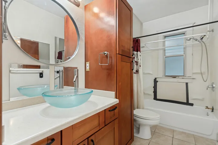 Bathroom featuring a vessel sink with a brushed nickel faucet, a white countertop, and wood-finish cabinetry