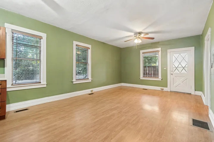 Spacious room featuring wood-finish flooring, light green walls, and white trim