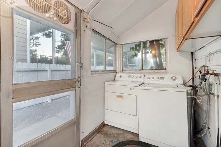 Utility room featuring a washer and dryer, sloped ceiling, and multiple windows providing natural light