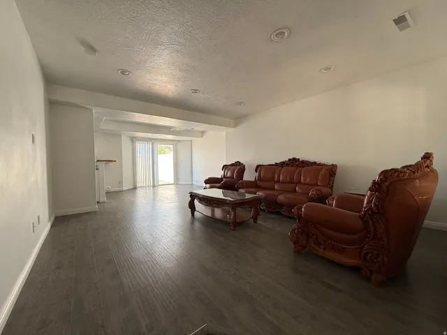 Spacious living room featuring wood-finish flooring, recessed ceiling lighting, and an open floor plan that extends toward the entry foyer and adjacent spaces