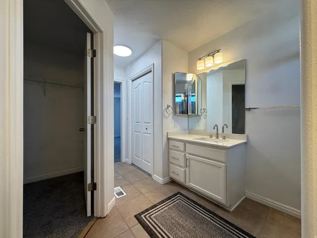 Bathroom vanity featuring a single sink, white cabinetry, and brushed nickel hardware