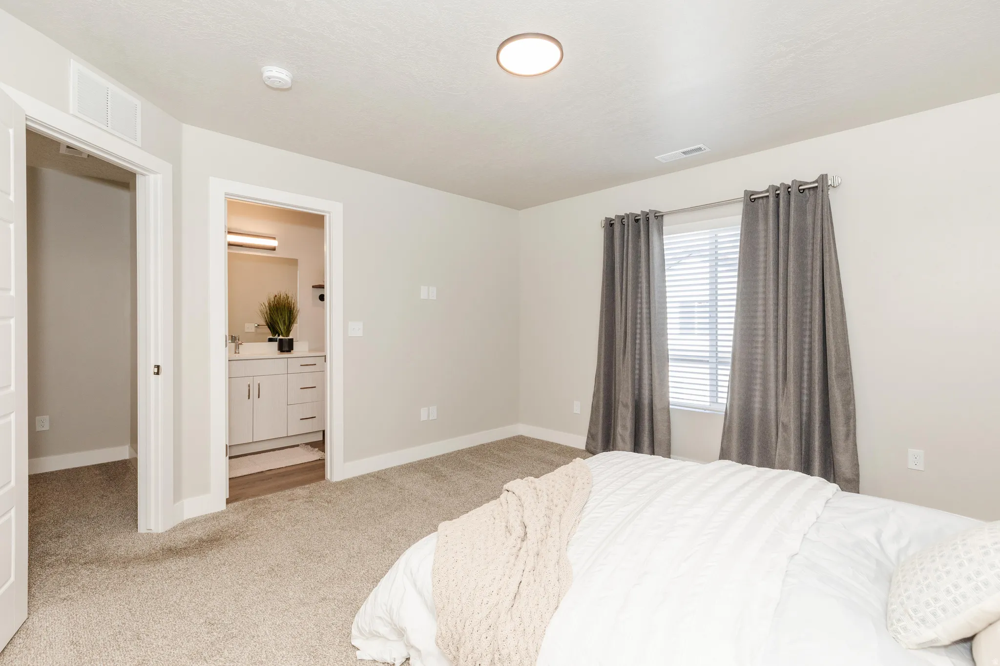 Spacious primary bedroom featuring neutral wall finishes, recessed ceiling lighting, and direct access to an ensuite bathroom