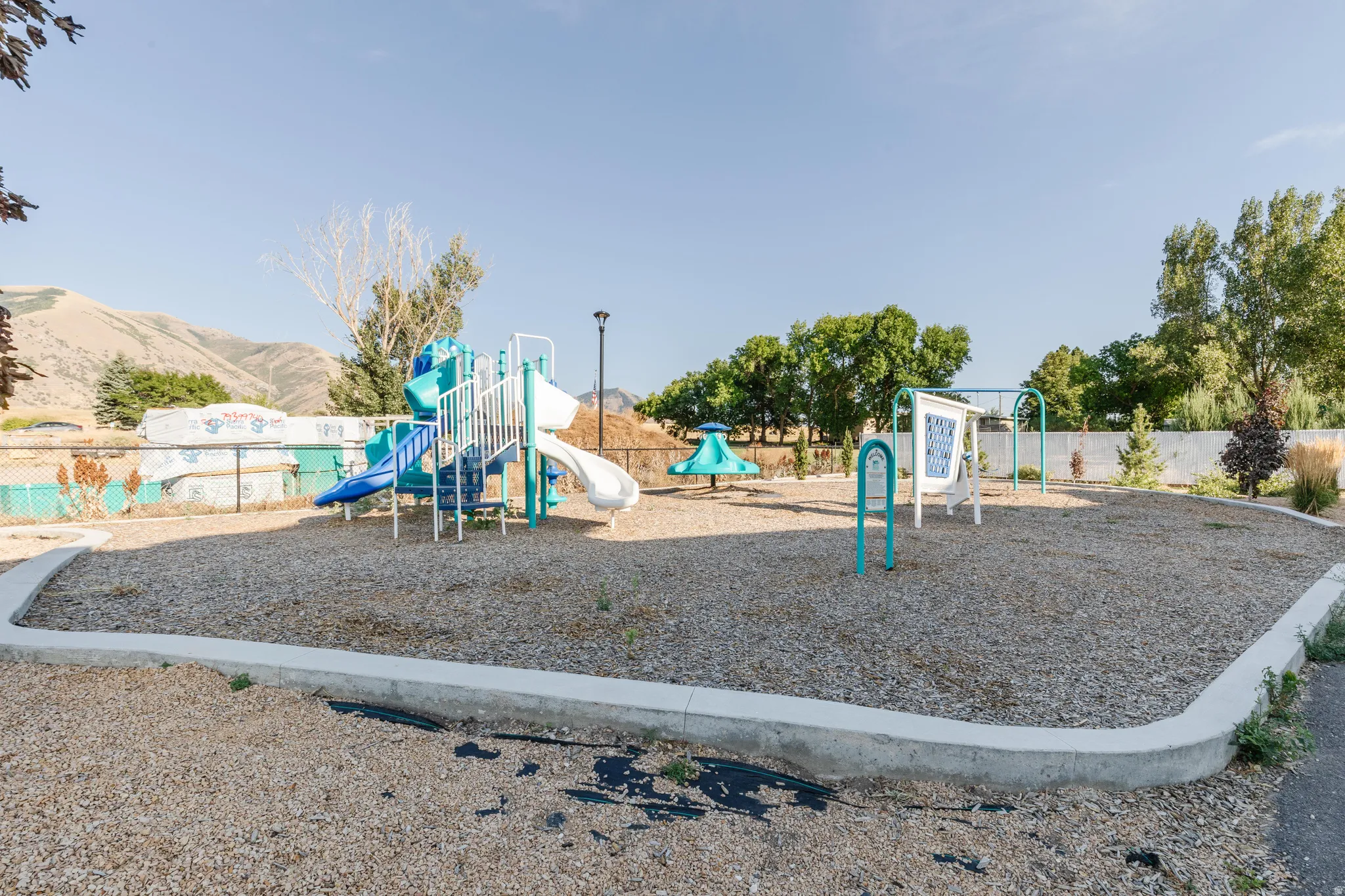 Outdoor play area featuring multiple structures, wood chip surfacing, and a concrete border