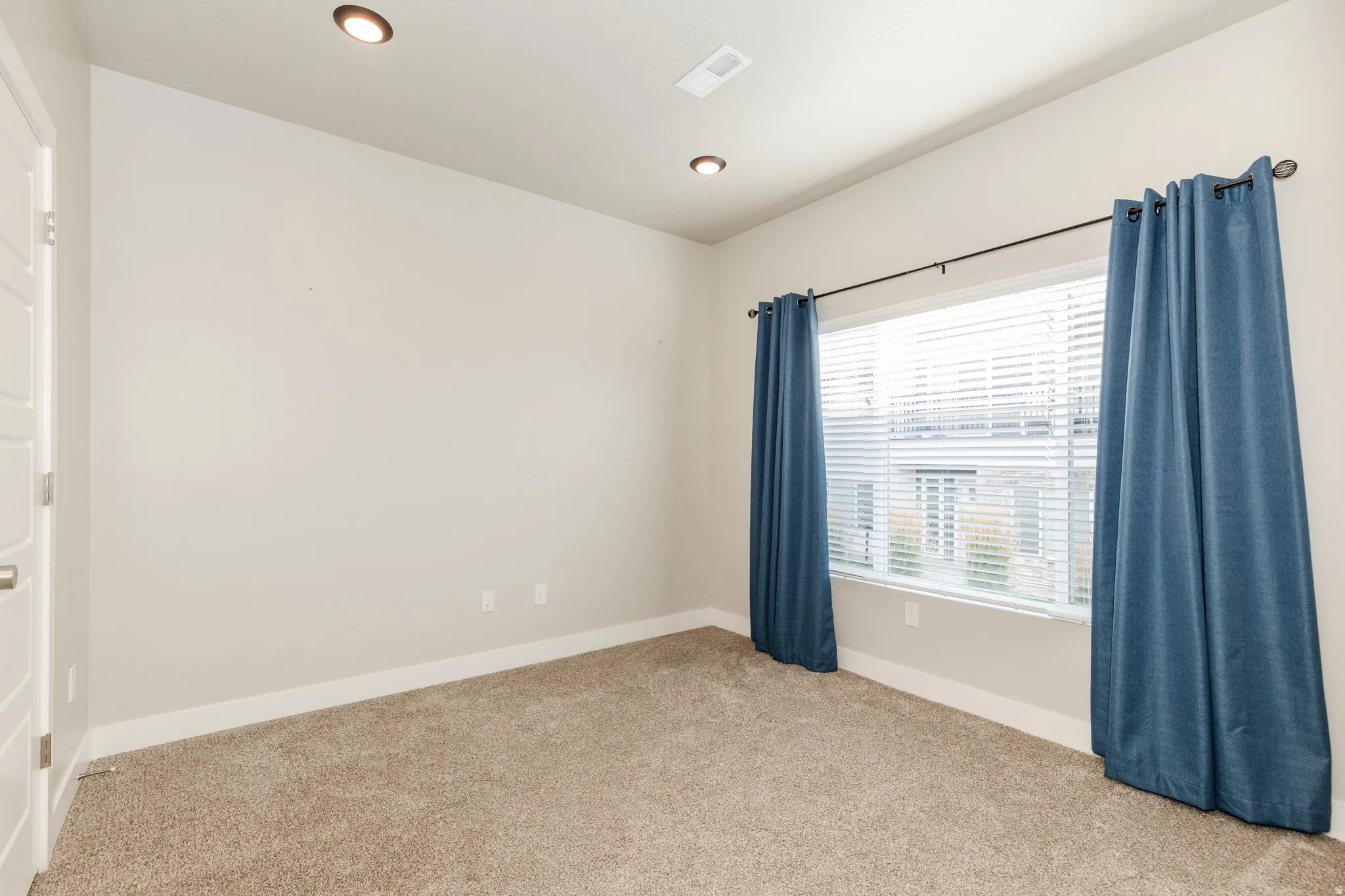 Expansive window with horizontal blinds and blue fabric curtains