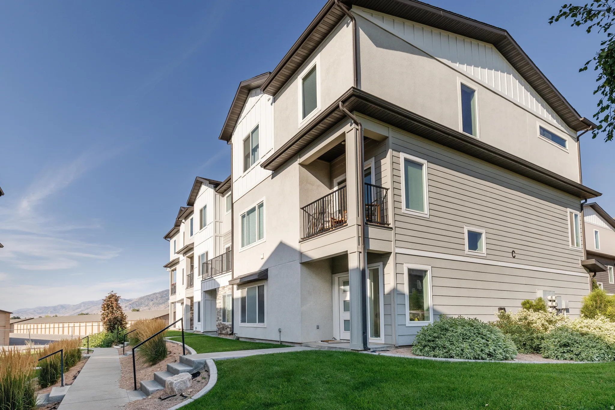 Multi-story residential building with light gray stucco and horizontal siding