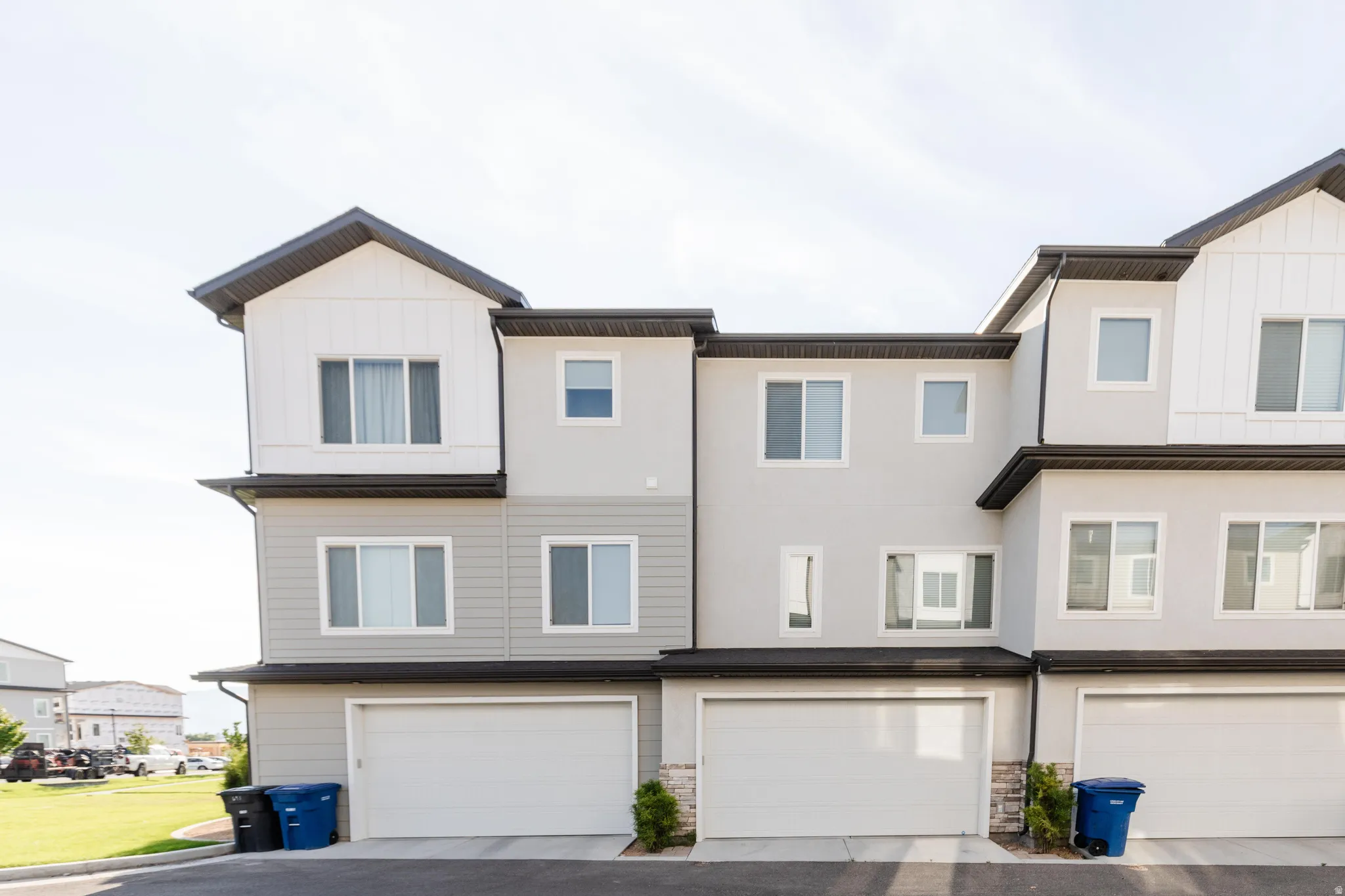 Modern townhome exterior featuring a multi-story design, a prominent gabled section with vertical siding, and a two-car garage
