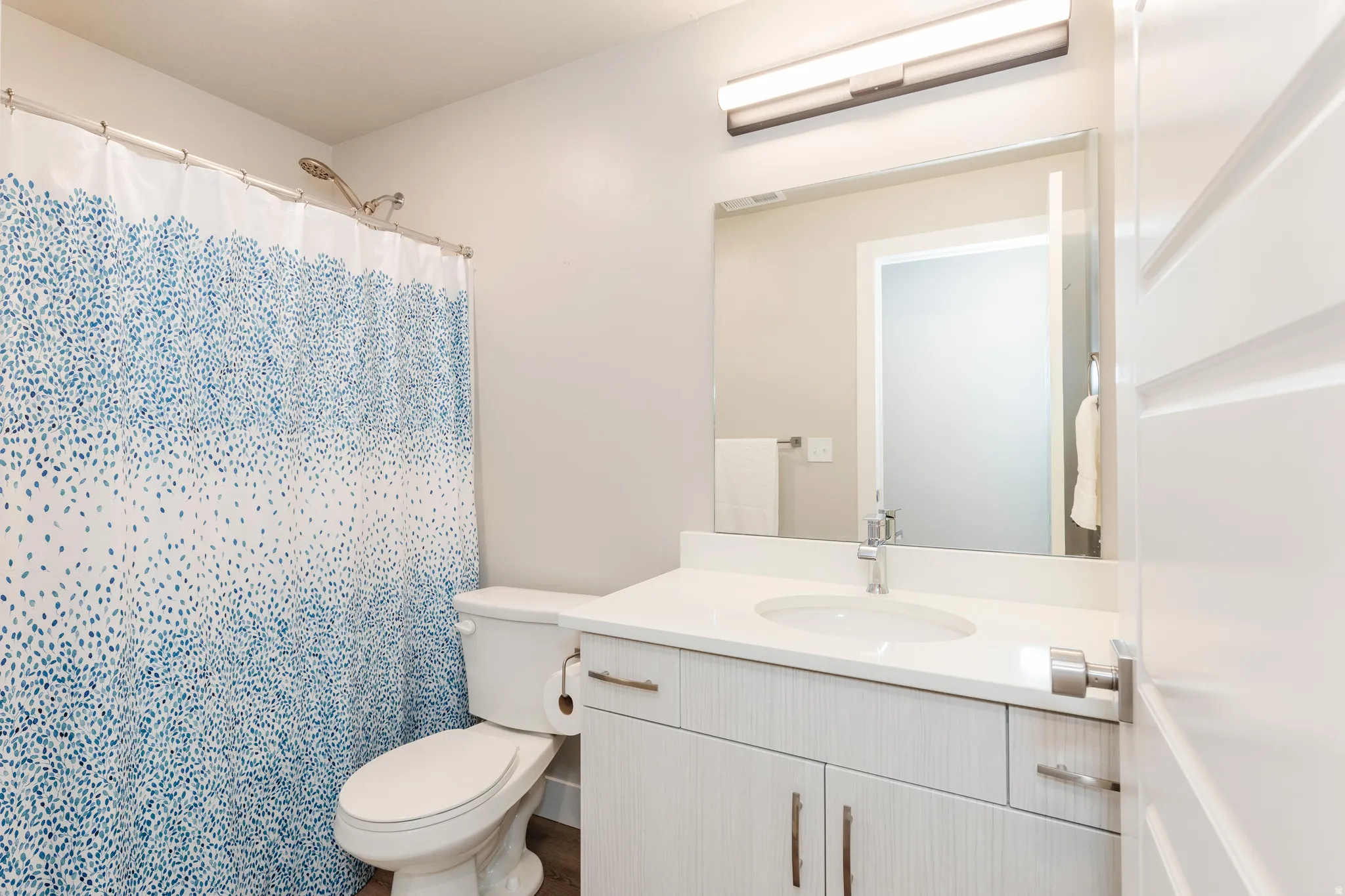 Full bathroom featuring a white vanity with integrated sink, chrome faucet, and rectangular mirror