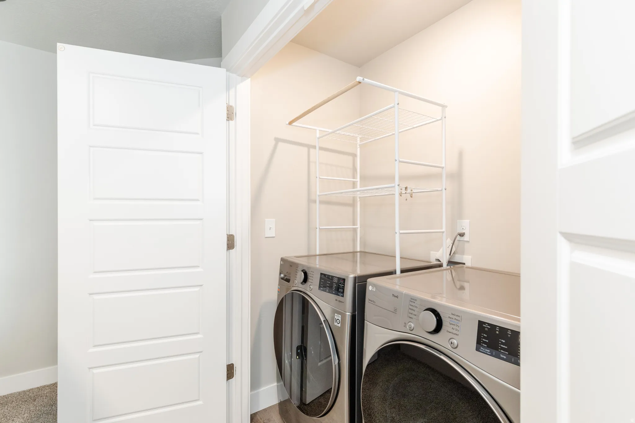 Dedicated laundry area featuring a white wire shelving unit above two front-load appliances