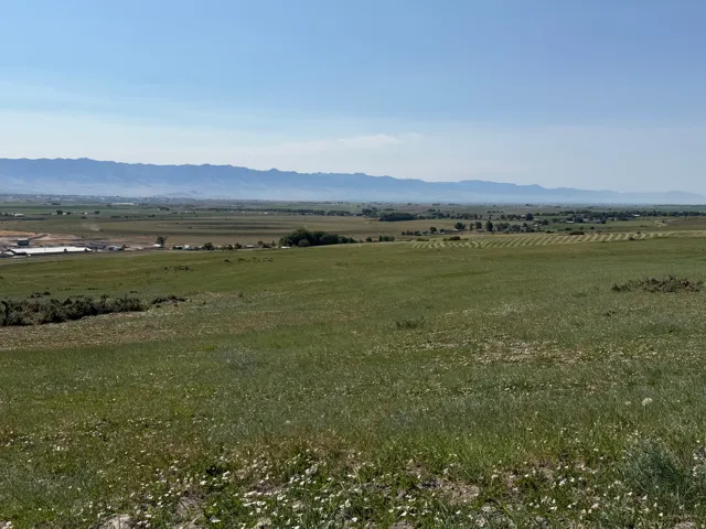 Expansive landscape featuring rolling green terrain and distant mountain ranges