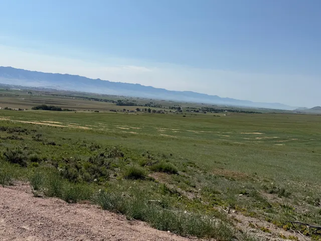 Expansive rural landscape featuring a vast, grassy field under a clear sky