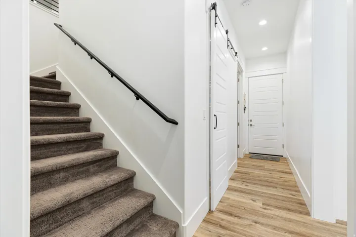 Interior hallway featuring wood-finish flooring, recessed lighting, and a white barn door with black hardware