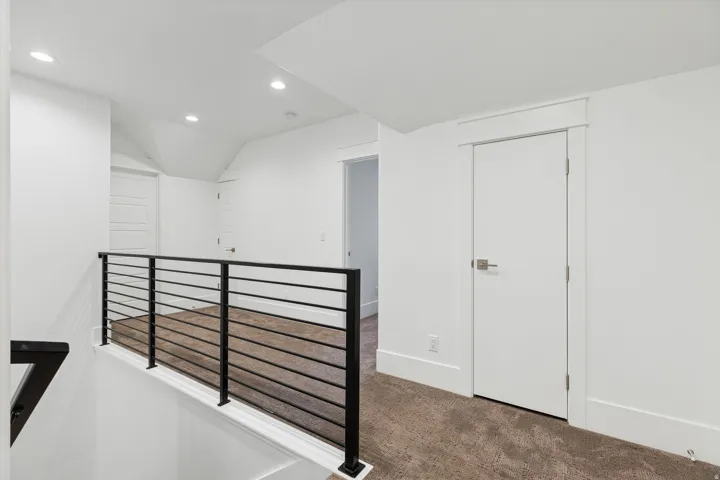 Second-level landing featuring a contemporary black metal horizontal railing, recessed lighting, white trim, and a neutral carpet