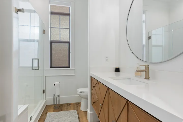 Contemporary bathroom featuring a floating wood-finish vanity with geometric drawer fronts, a white countertop, and an integrated sink
