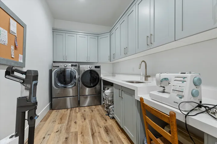 Dedicated utility room featuring light wood-finish flooring, light gray cabinetry, and white countertops