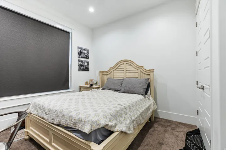 Neutral wall tones with recessed lighting, a wide window with roller shade, plush carpet flooring, and a modern paneled door with contemporary hardware