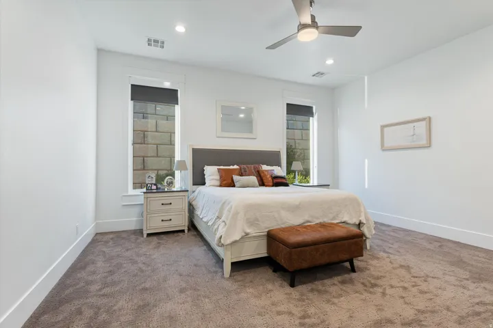 Carpeted room featuring a ceiling fan with integrated lighting, recessed lighting, and two windows with roller shades