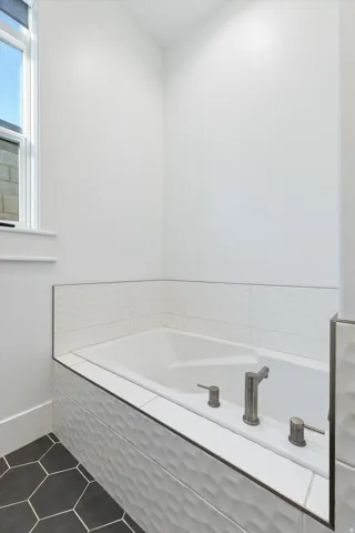 Built-in soaking tub with textured tile surround and brushed nickel fixtures
