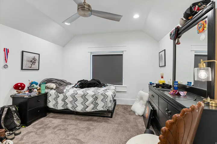 Carpeted room featuring a sloped ceiling with a recessed light and ceiling fan