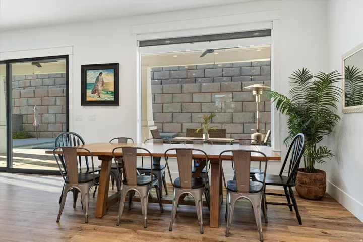 Spacious dining area featuring wood-finish flooring and a wide window opening to an outdoor patio with block walls
