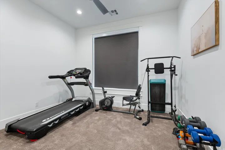 Carpeted room with a ceiling fan, recessed lighting, and a window with a roller shade