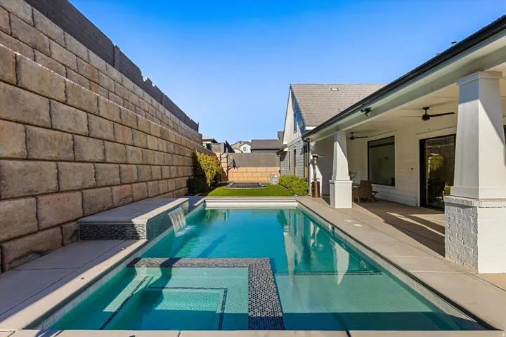 Resort-style backyard featuring a rectangular swimming pool with integrated spa and waterfall feature