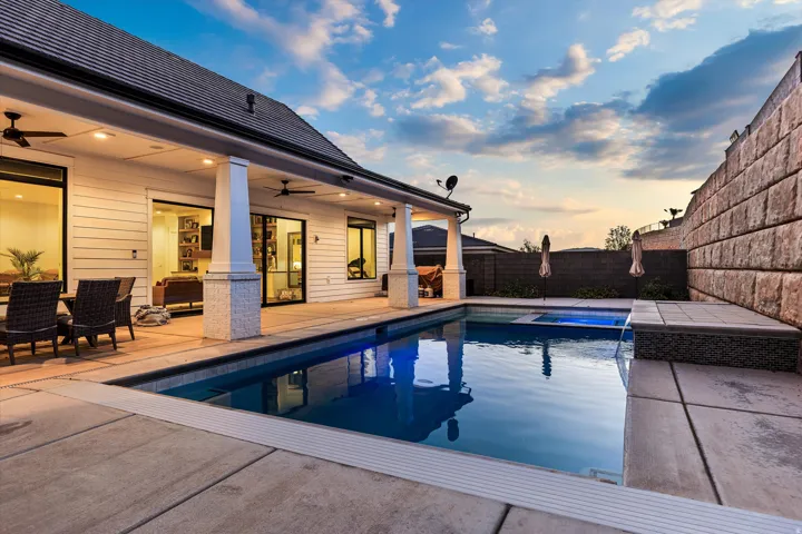 Backyard retreat featuring a rectangular swimming pool, integrated spa, and waterfall feature