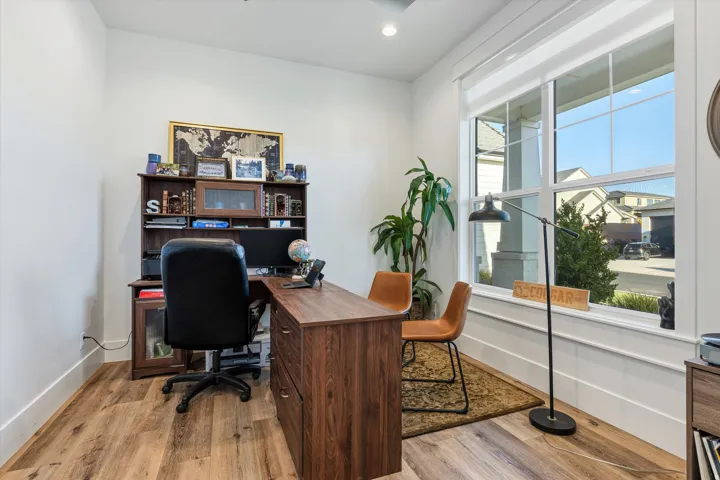 Dedicated room featuring wood-finish flooring, a large multi-pane window, white walls, and bright recessed lighting