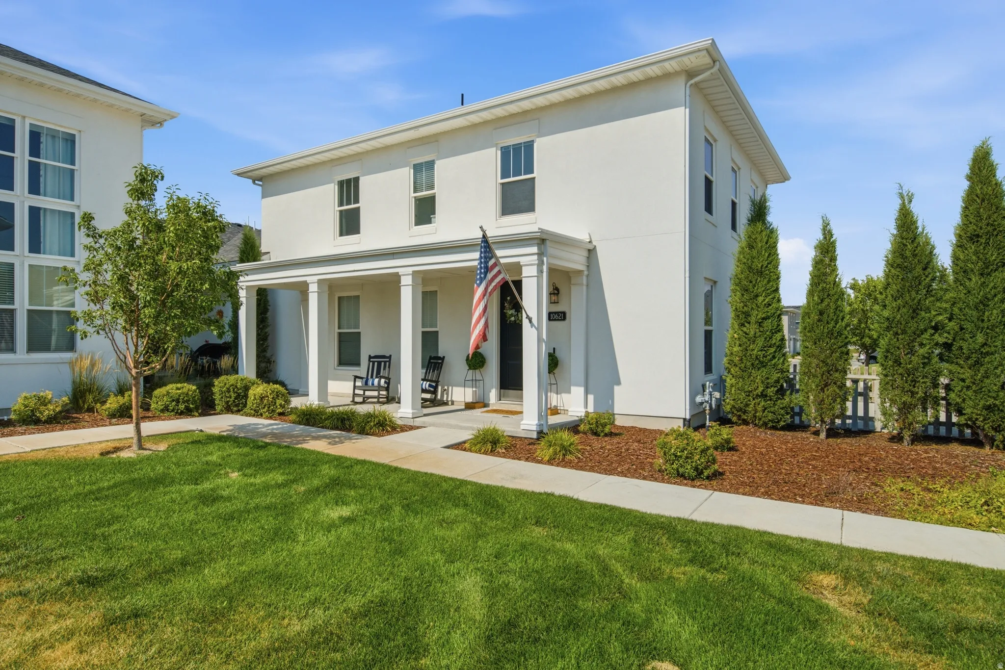 Two-story residence featuring a white stucco exterior with a covered porch supported by four columns