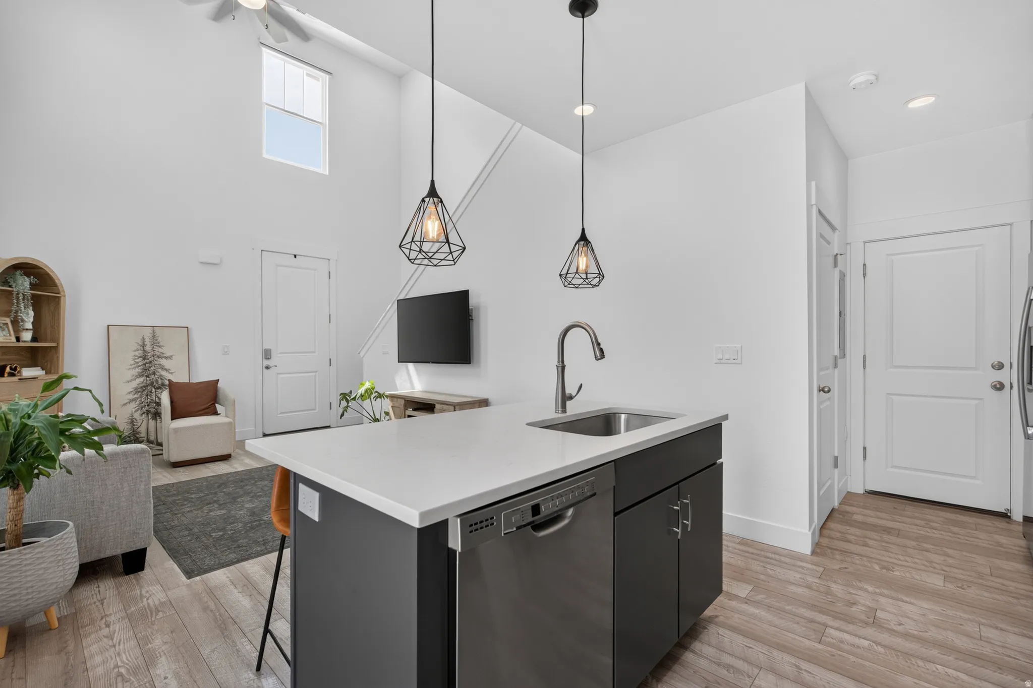 Kitchen island featuring a white countertop, undermount stainless steel sink, and integrated dishwasher