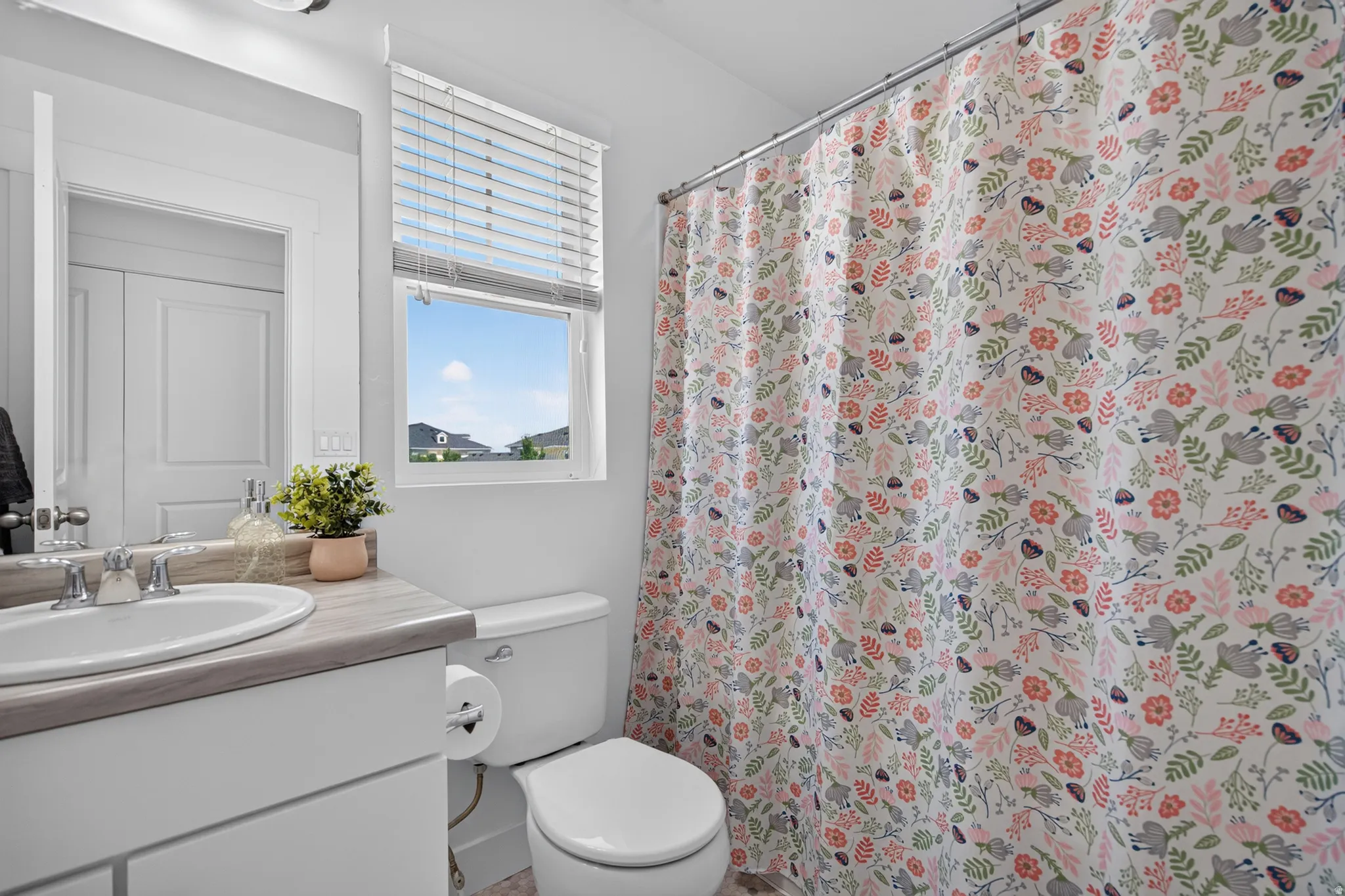 Bright bathroom featuring a curved vanity with integrated sink, gray countertop, and chrome fixtures