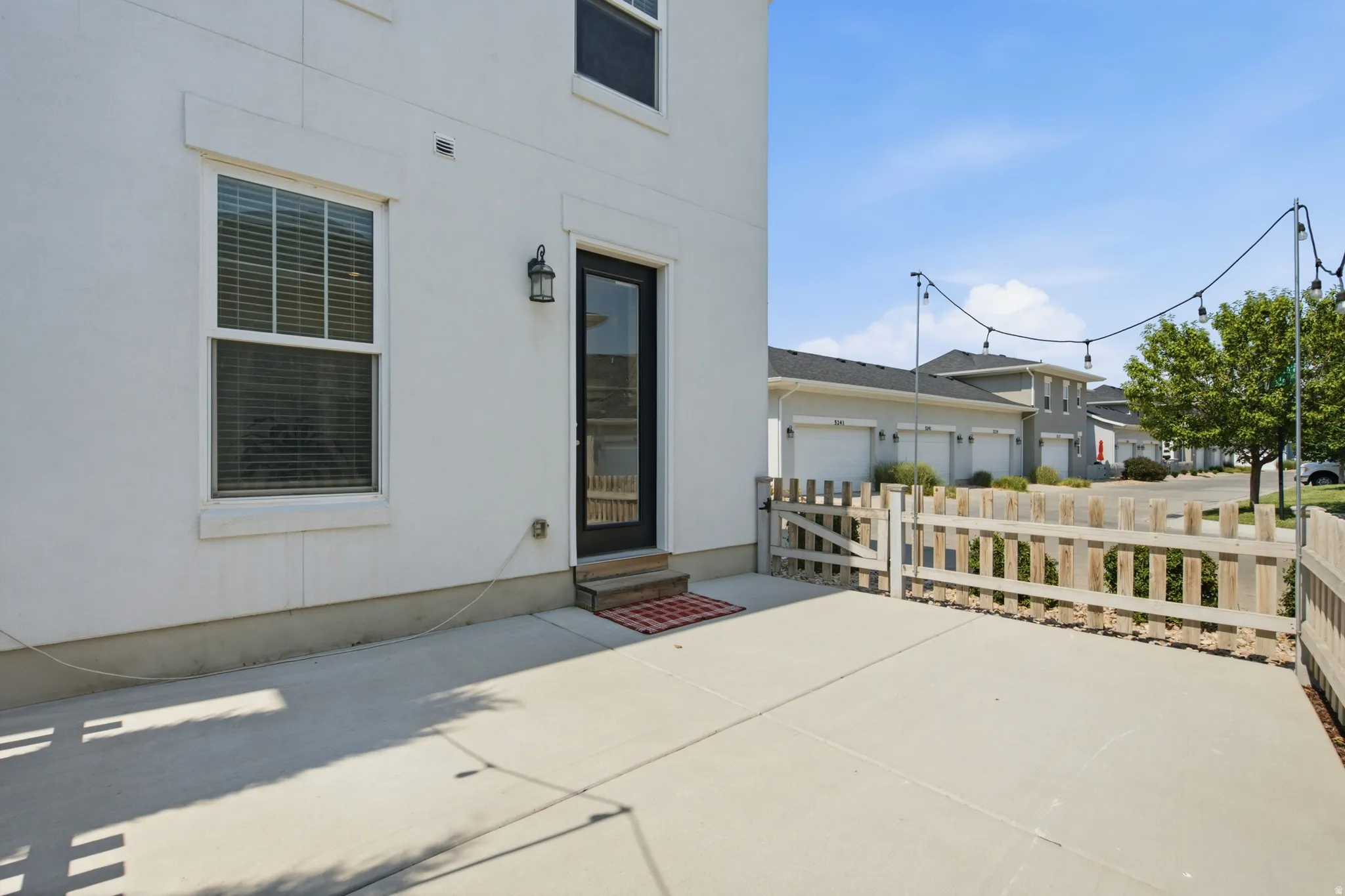 Private concrete patio area with a wooden picket fence and gated access