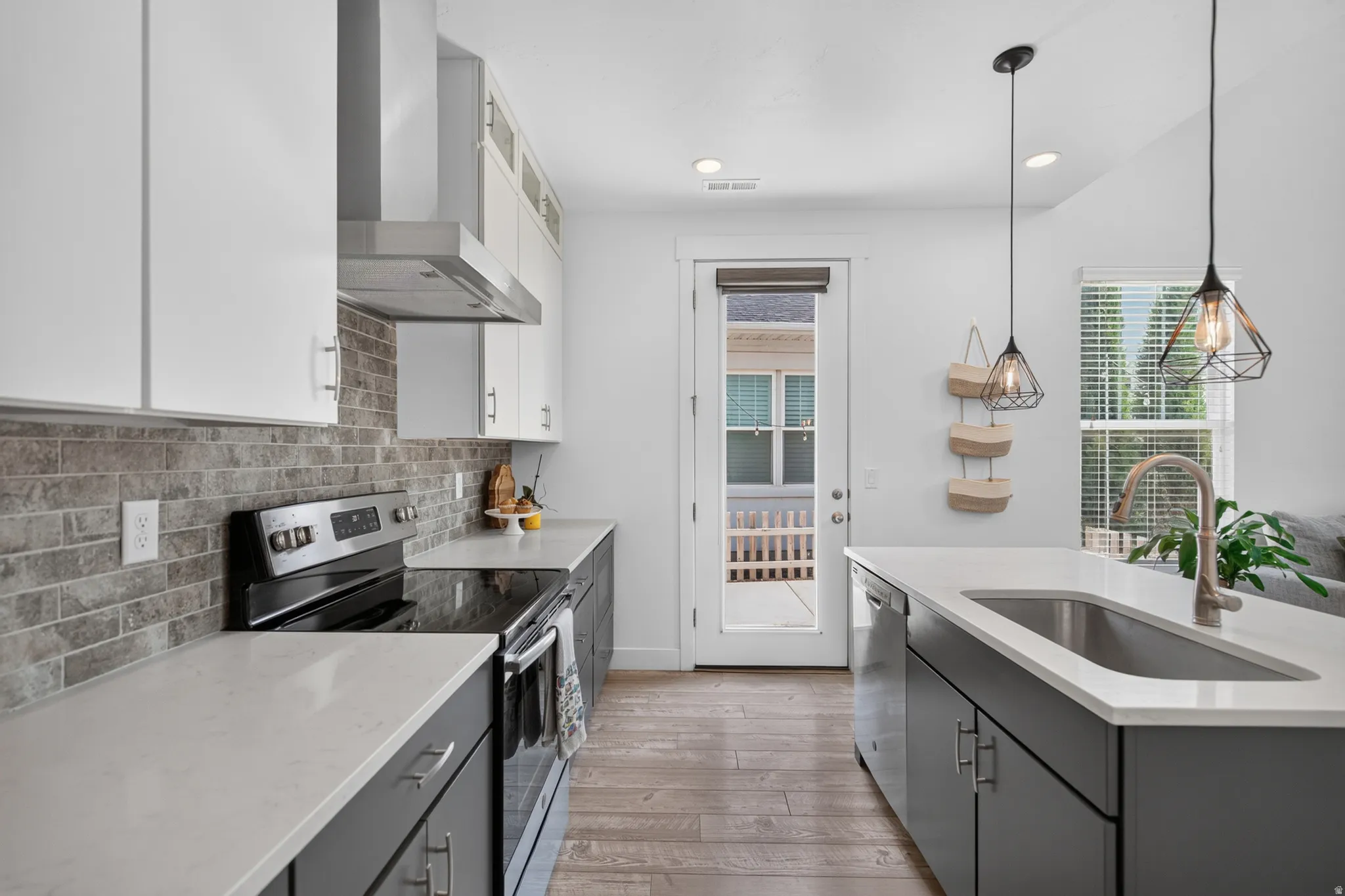 Modern kitchen featuring two-tone cabinetry, light-toned countertops, and a subway tile backsplash