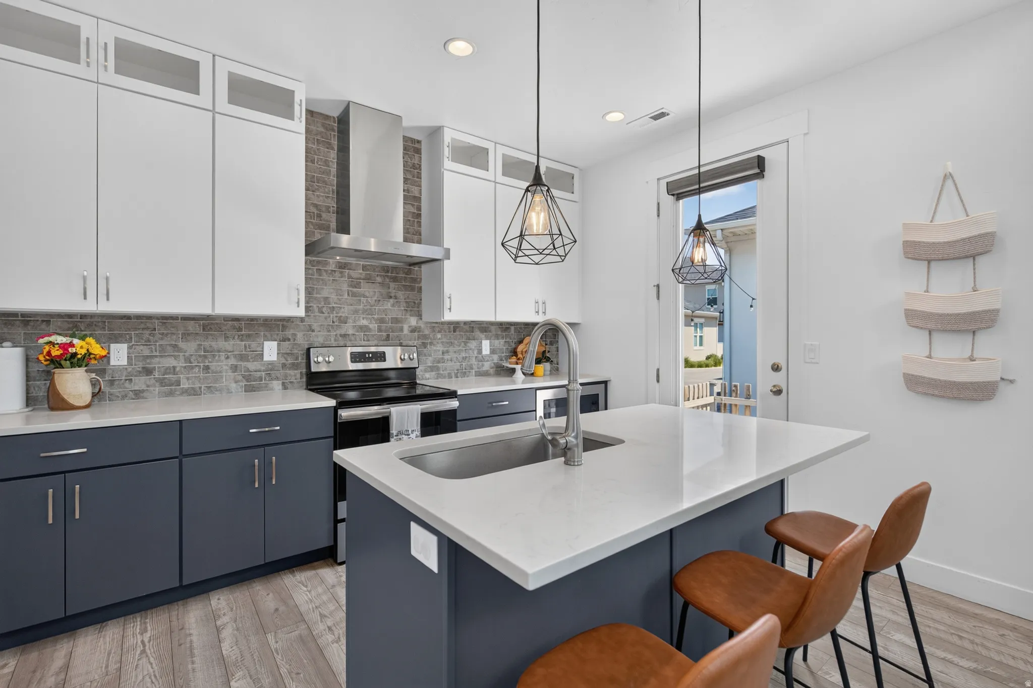 Modern kitchen featuring two-tone cabinetry, stainless steel appliances, a tile backsplash, and wood-finish flooring