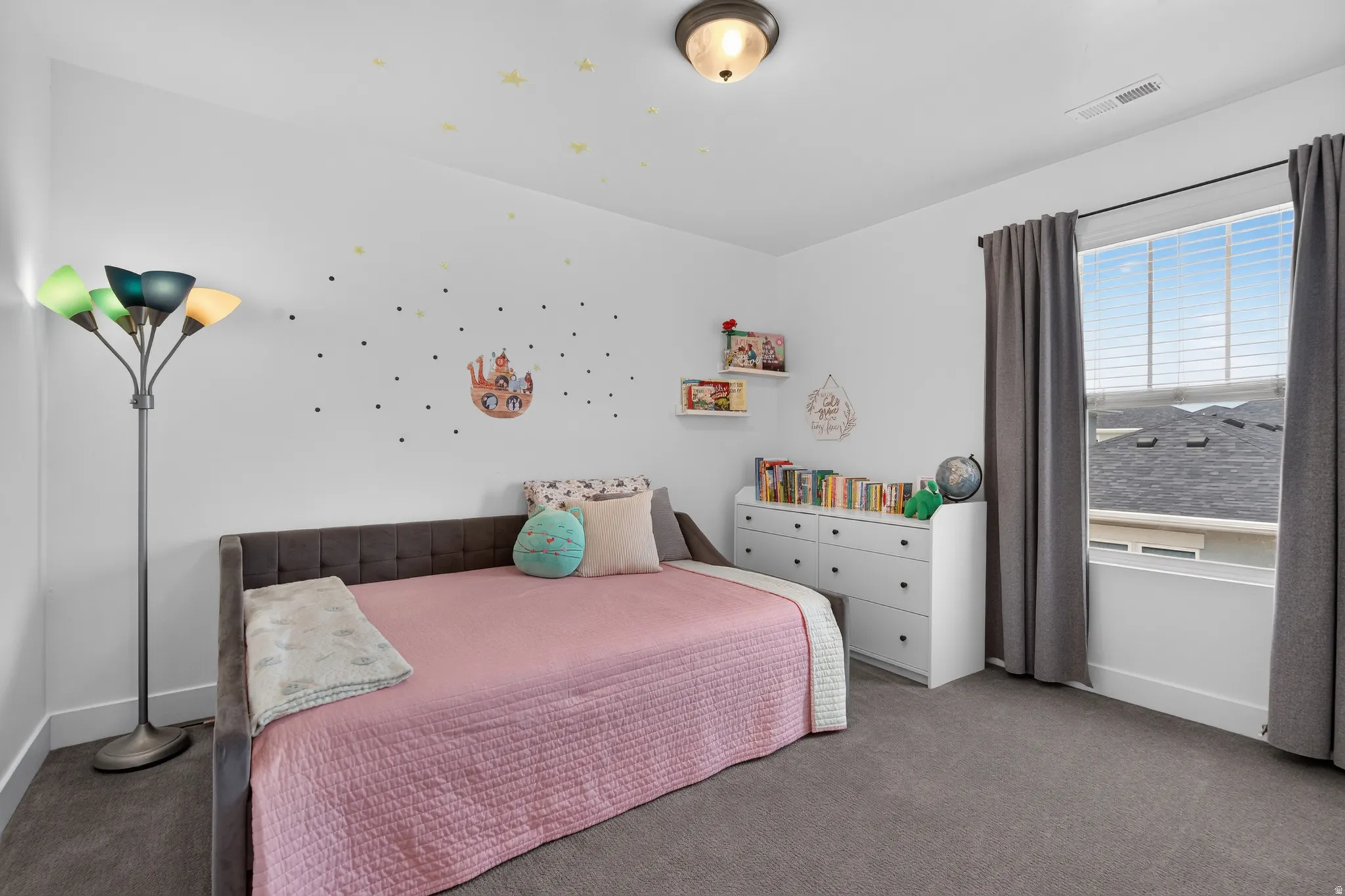 Bright room featuring a large window with blinds and gray curtains, a flush-mount ceiling light fixture, and gray carpet flooring