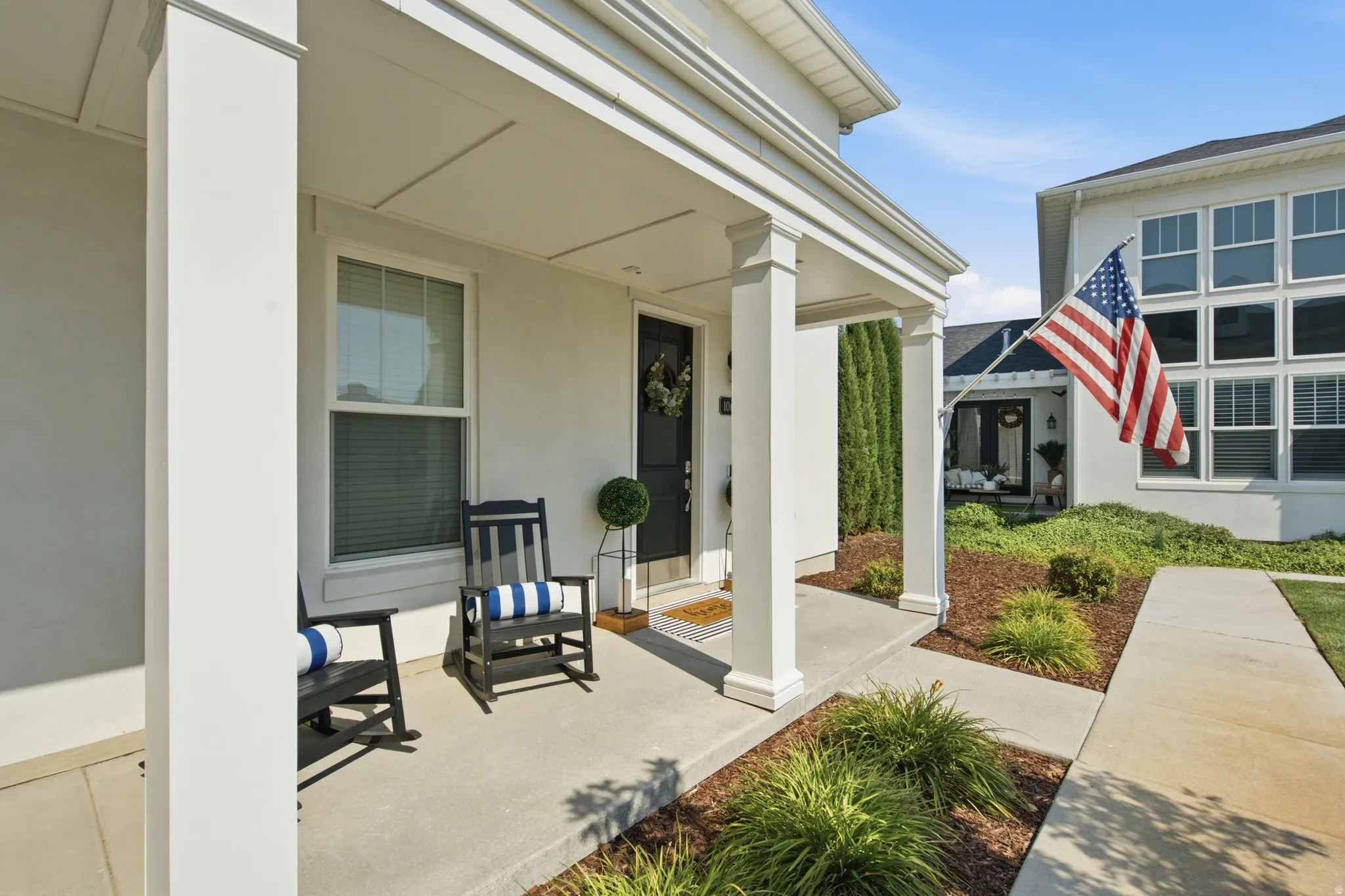 Covered porch entrance featuring white columns and a black front door