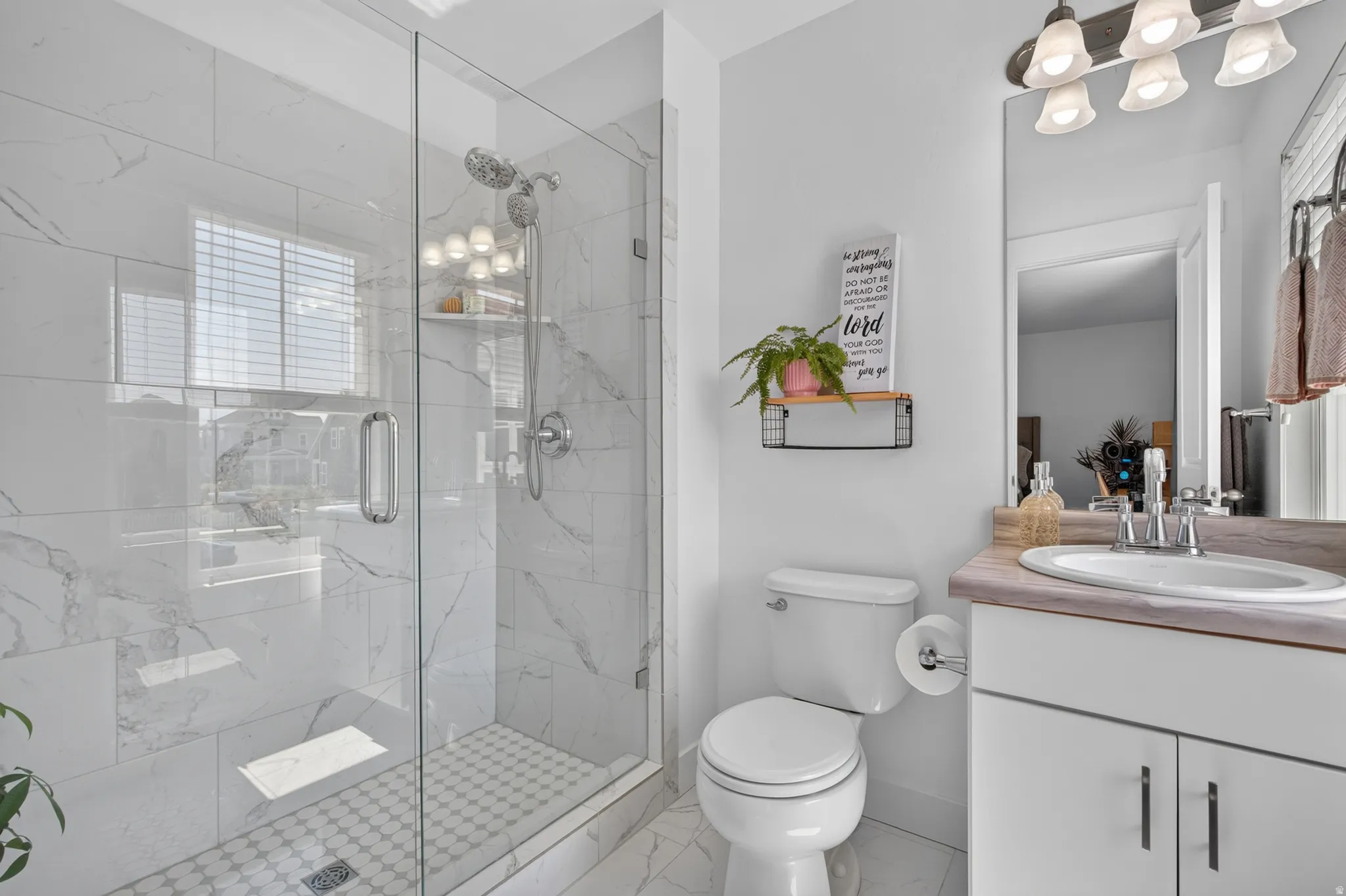 Contemporary bathroom featuring a glass-enclosed shower with white marble-patterned tile, a coordinating hexagonal mosaic shower floor, and a polished chrome dual shower head system
