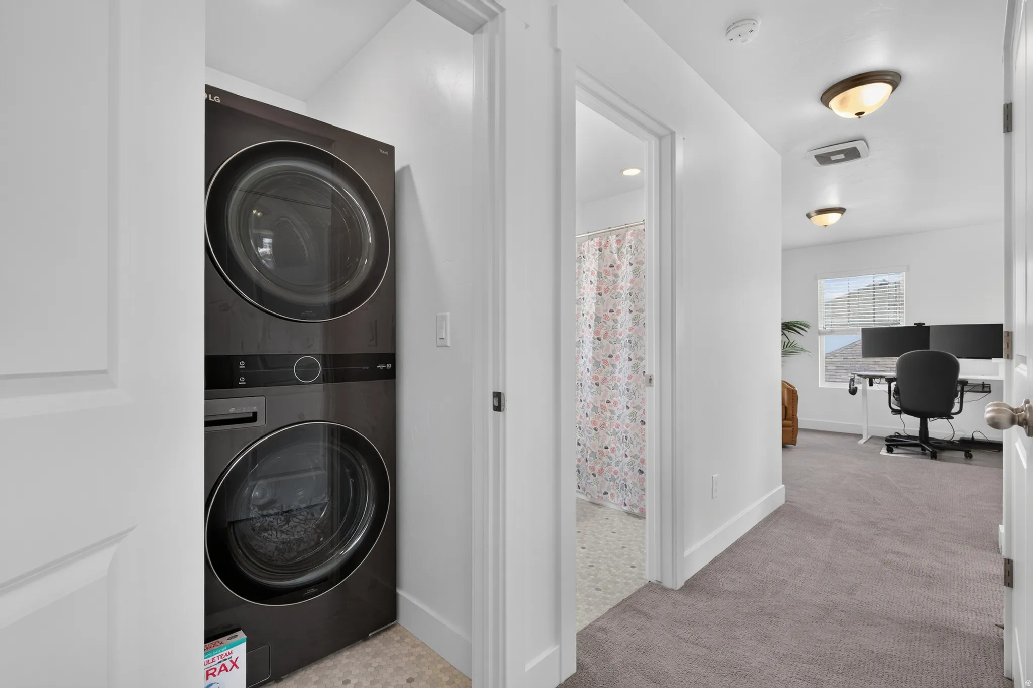 Dedicated laundry area featuring a stacked washer and dryer unit