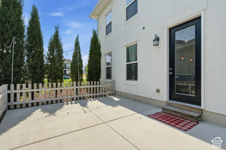 Concrete patio with a white picket fence and privacy landscaping