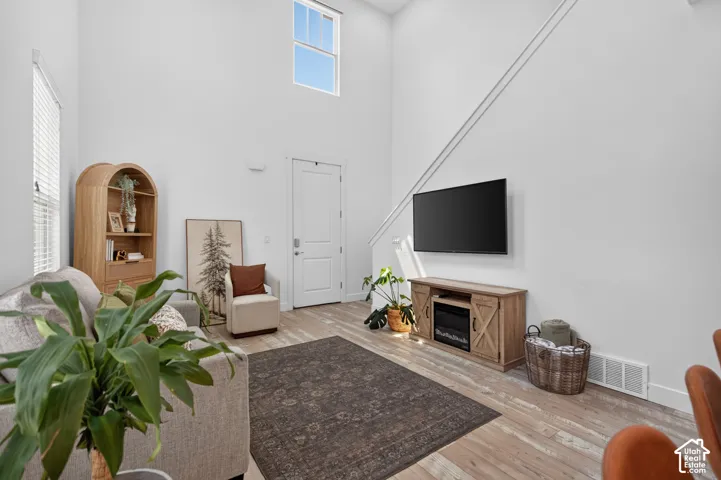 Two-story living area featuring wood-finish flooring, a contemporary accent wall, and a high window