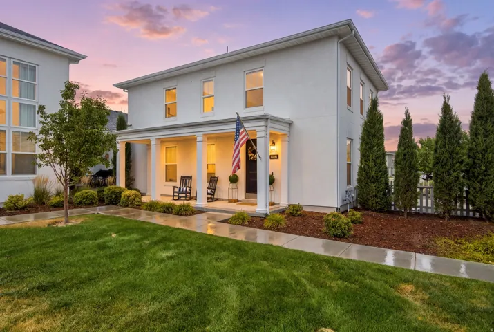 Two-story stucco exterior featuring a covered porch with column supports
