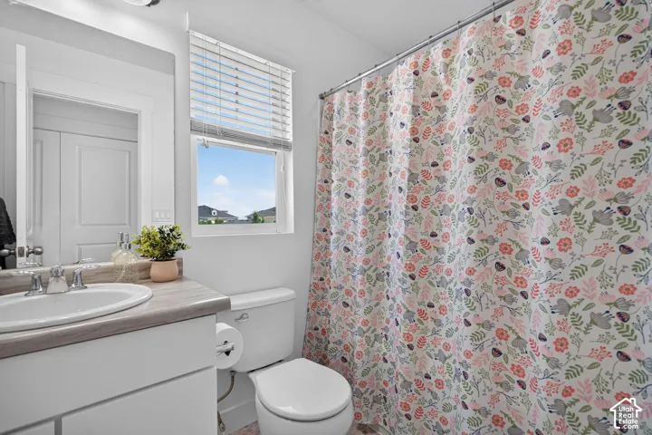 Bright bathroom featuring a curved vanity with integrated sink, gray countertop, and chrome fixtures