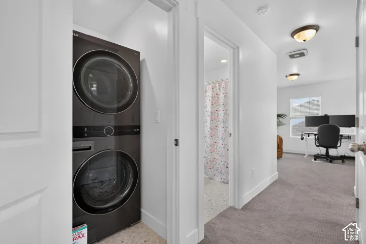 Dedicated laundry area featuring a stacked washer and dryer unit