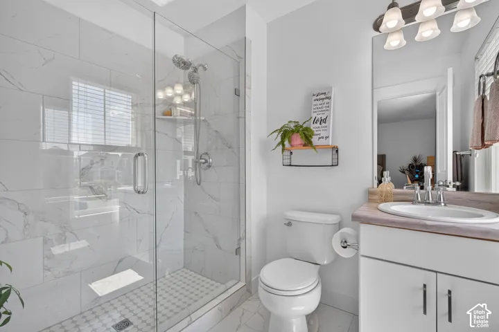 Contemporary bathroom featuring a glass-enclosed shower with white marble-patterned tile, a coordinating hexagonal mosaic shower floor, and a polished chrome dual shower head system