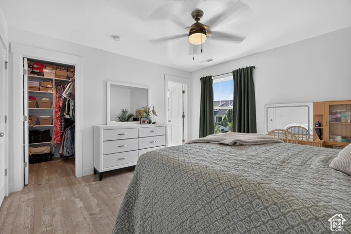 Bedroom featuring wood-finish flooring, a ceiling fan with integrated lighting, and a window with dark curtain rods