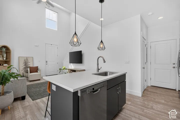 Kitchen island featuring a white countertop, undermount stainless steel sink, and integrated dishwasher