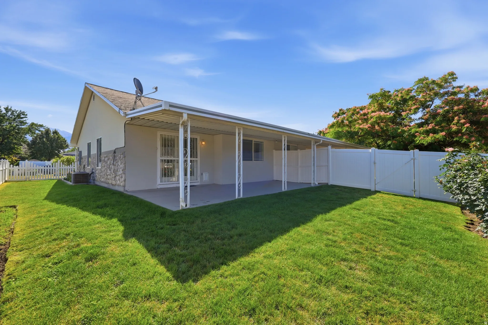 Expansive backyard featuring a covered patio, a white picket fence, and a full-height privacy fence