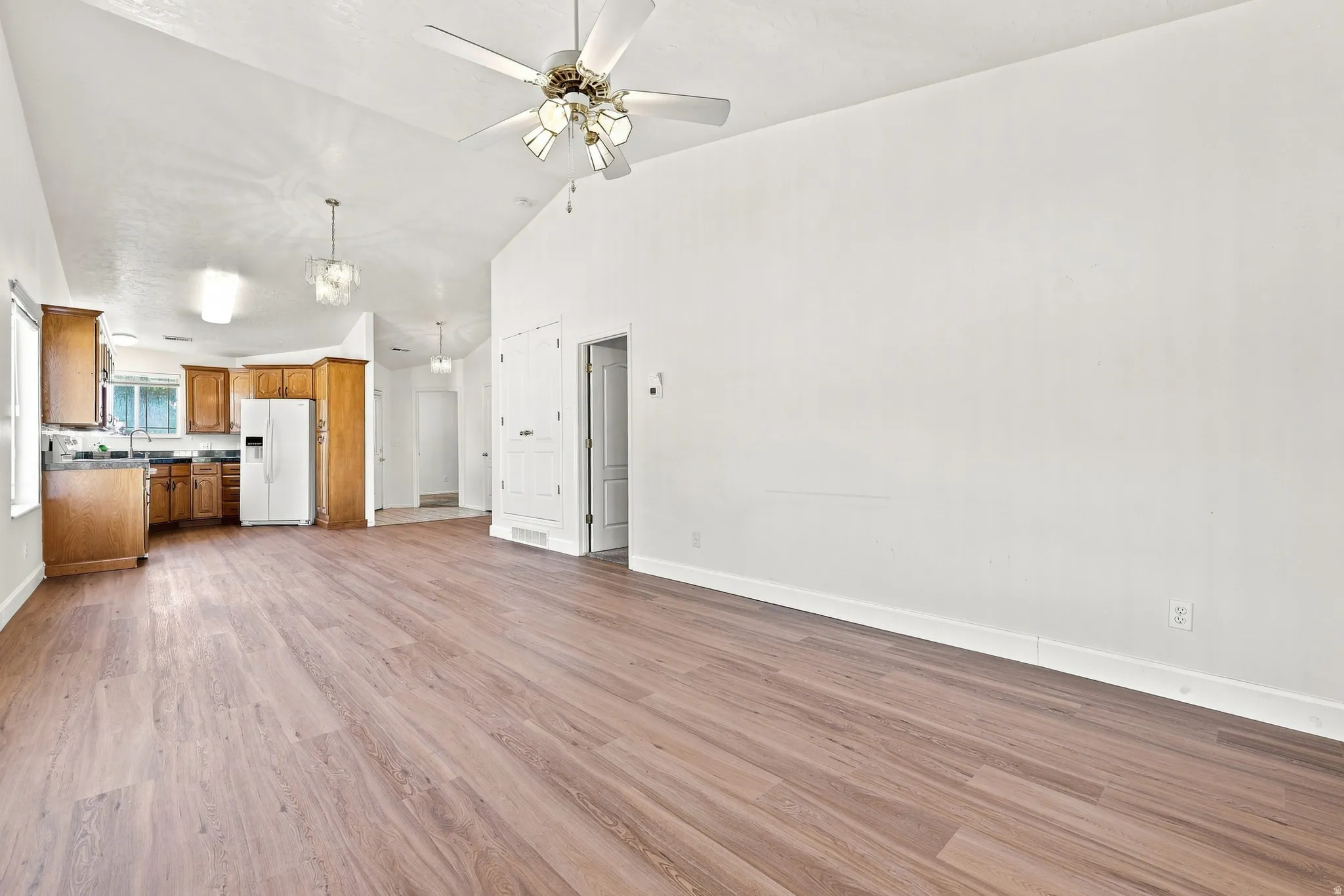 Spacious interior featuring wood-finish flooring, vaulted ceilings, and a ceiling fan